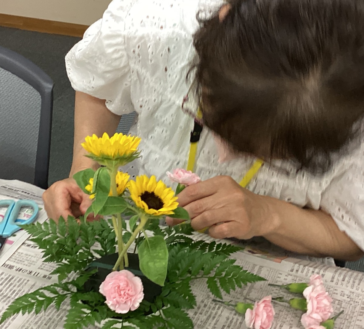 参加者が手元のフラワーアレンジメントを覗き込みながら、切った花を挿している様子。