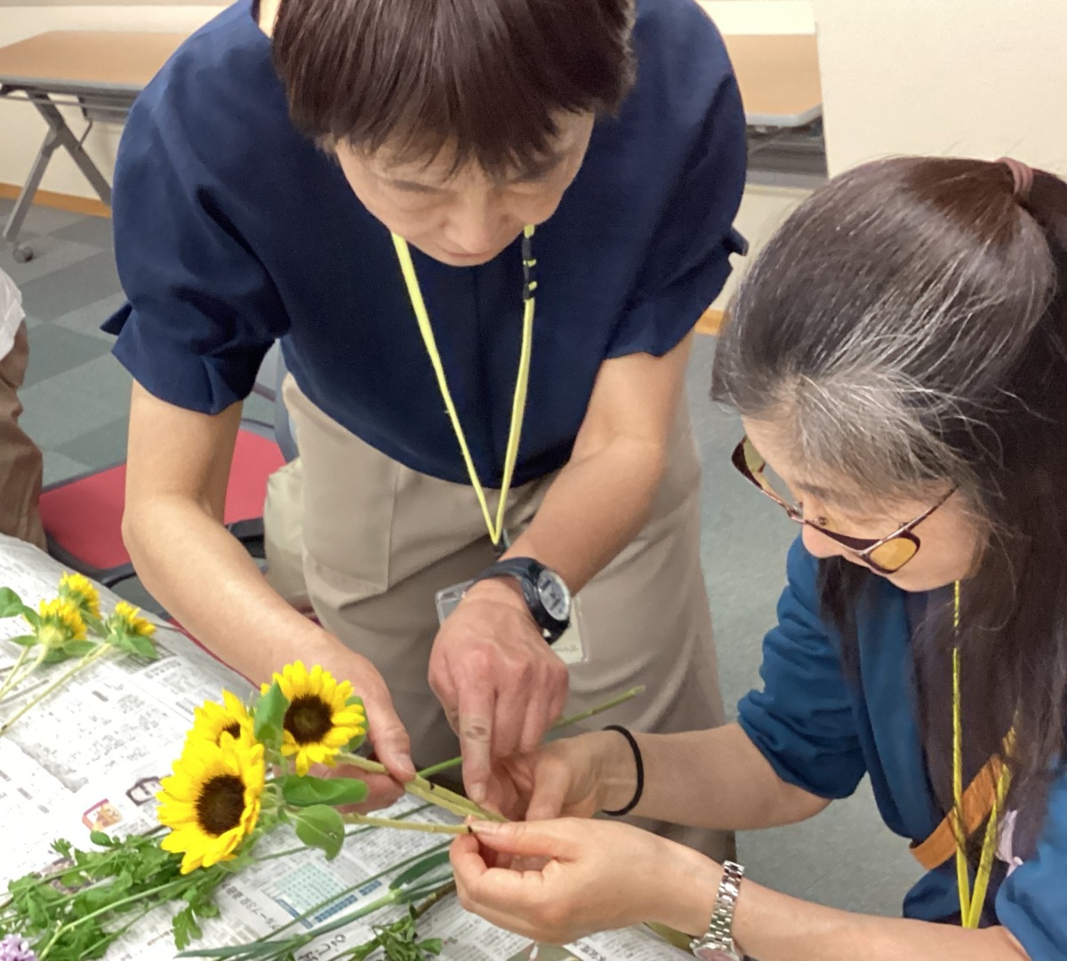 参加者と職員がひまわりの茎に付けられた印を、共に確認している様子。