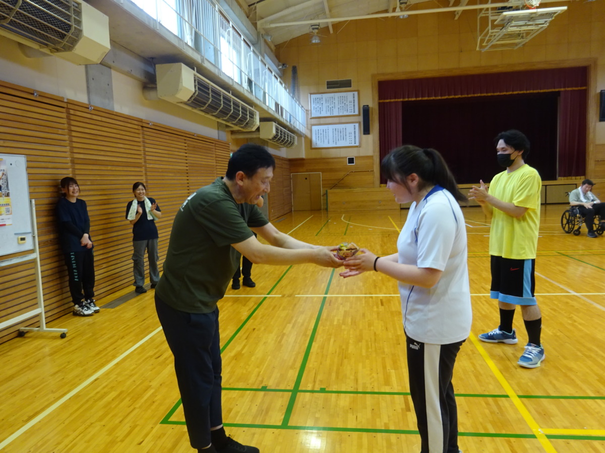 勝利チームキャプテンの生徒に、優勝カップが手渡されている様子。