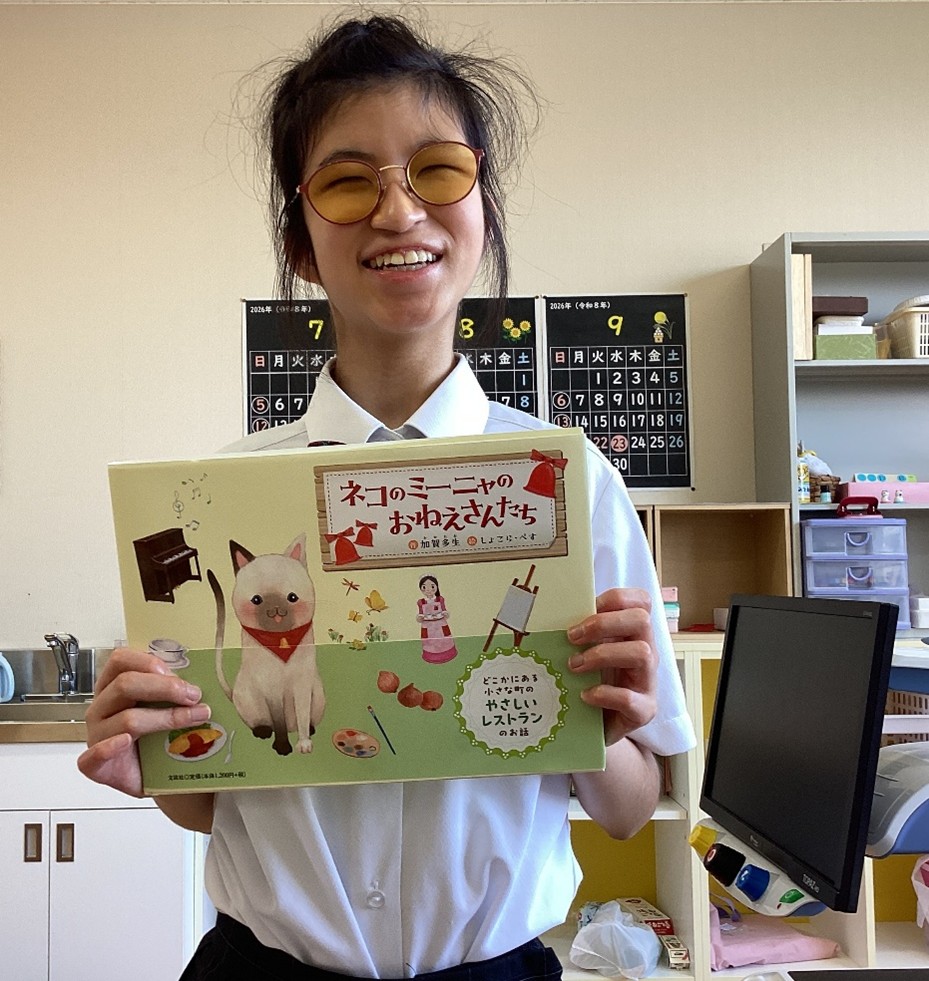 頂いた点字絵本を持ち、笑顔で写真に写る中学部生徒1名