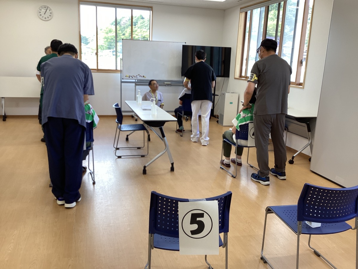 二列に並んだ4つの椅子に参加者が腰かけ、本校生徒が一人一人の施術に当たっている様子。