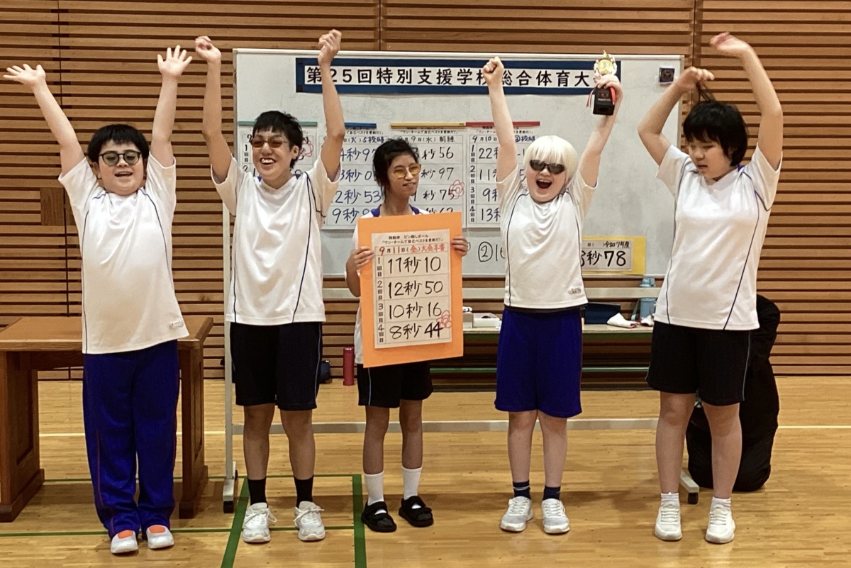 横一列に並んだ生徒のうち、中央の生徒が記録表を持ち、周りの生徒が万歳をしている様子。