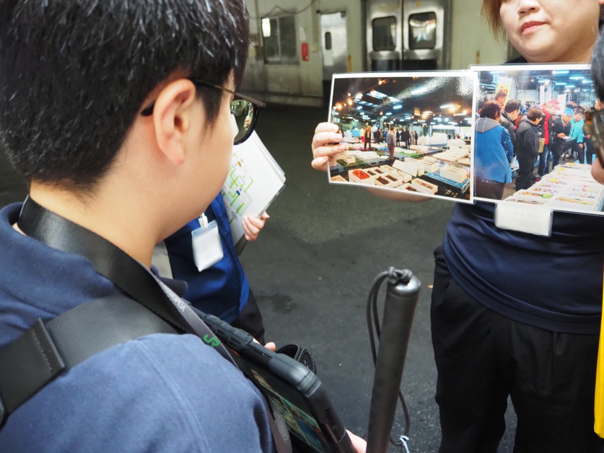 水産物の「せり」を写真で見せてもらっている児童