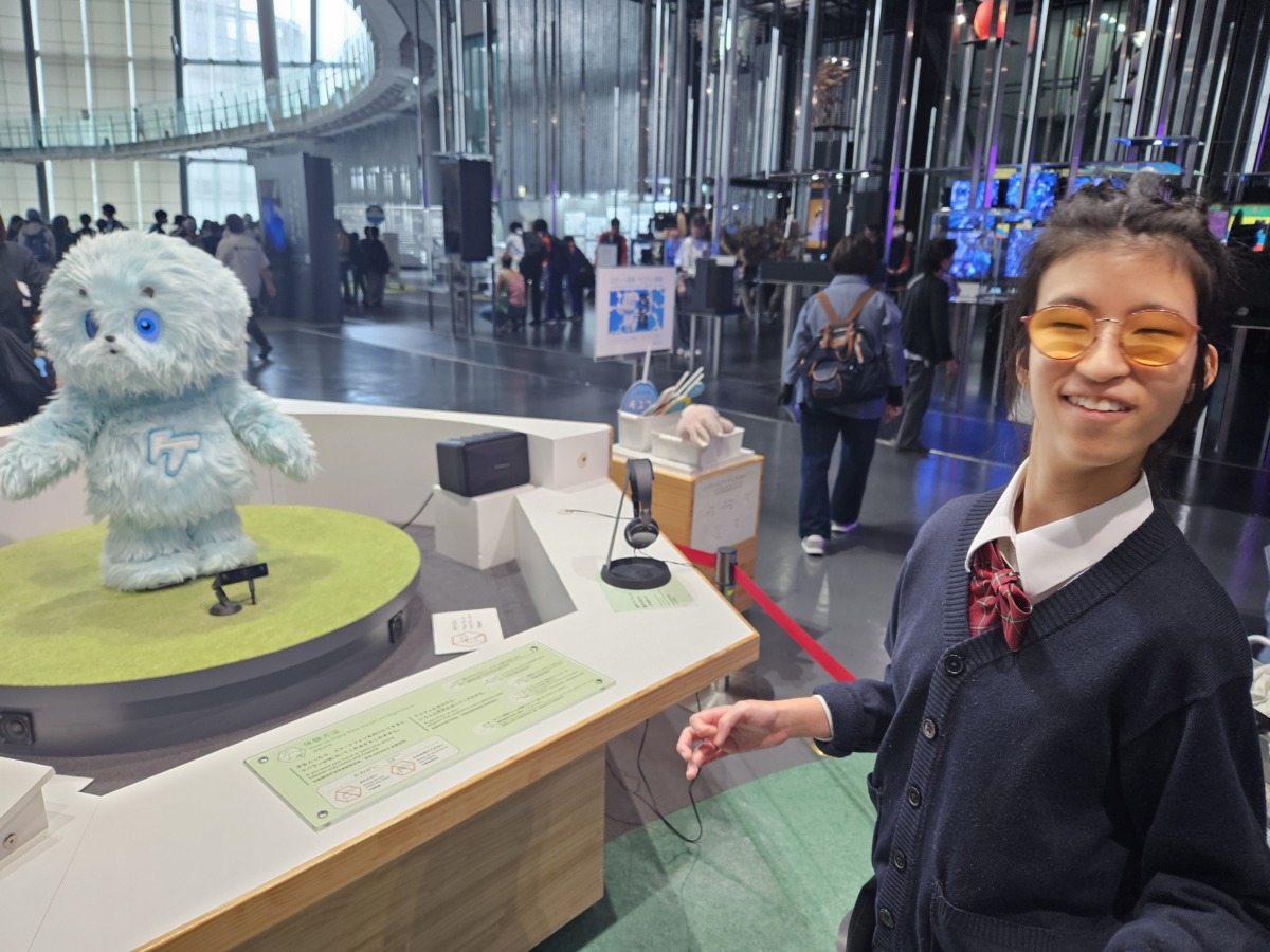 薄い水色をした二頭身の毛むくじゃらのロボットを傍で眺めている生徒