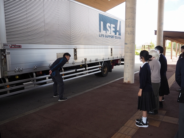 校舎の正面玄関前に大きな荷台を積んだトラックが停車している。